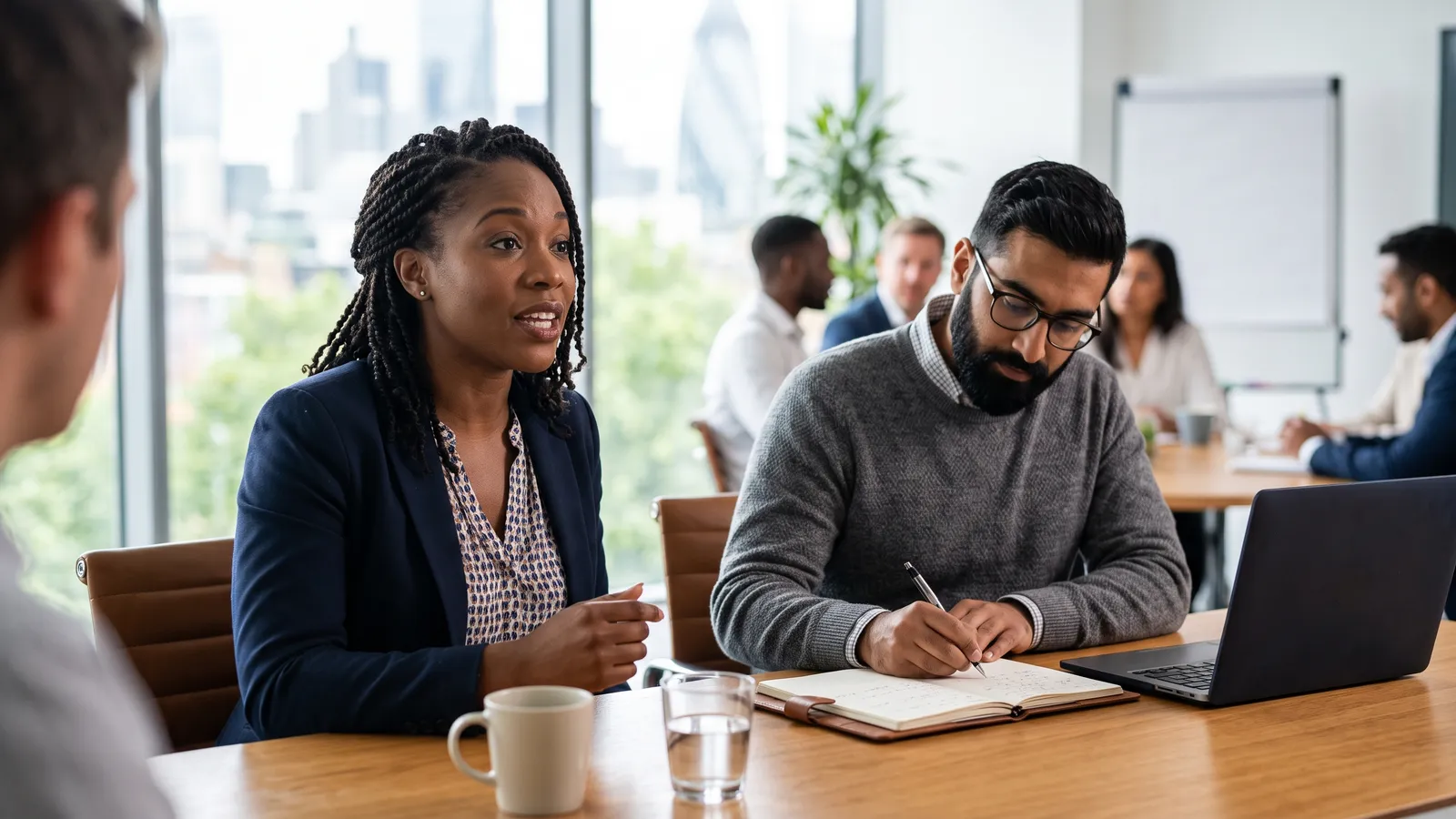 Colleagues in a meeting: one answering a question live while another takes notes
